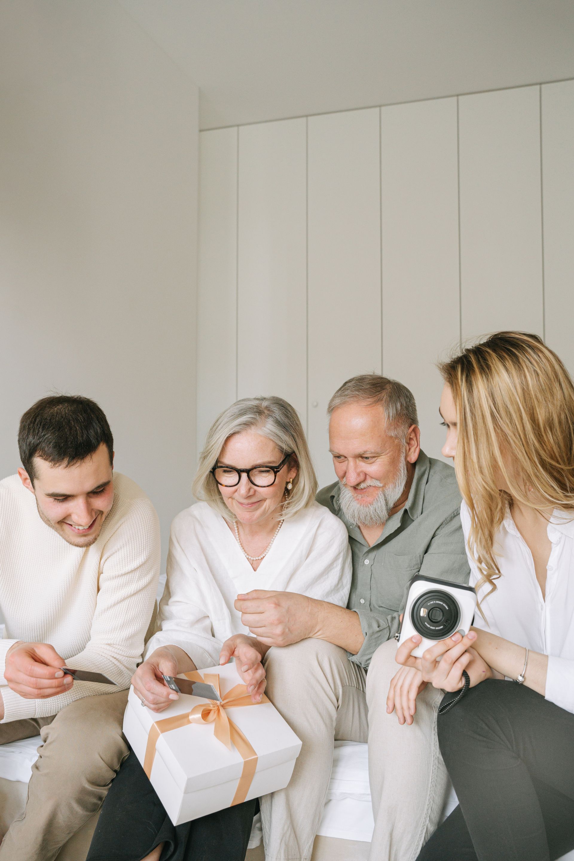 A family sits close together, smiling warmly in an easy, unhurried moment at home.